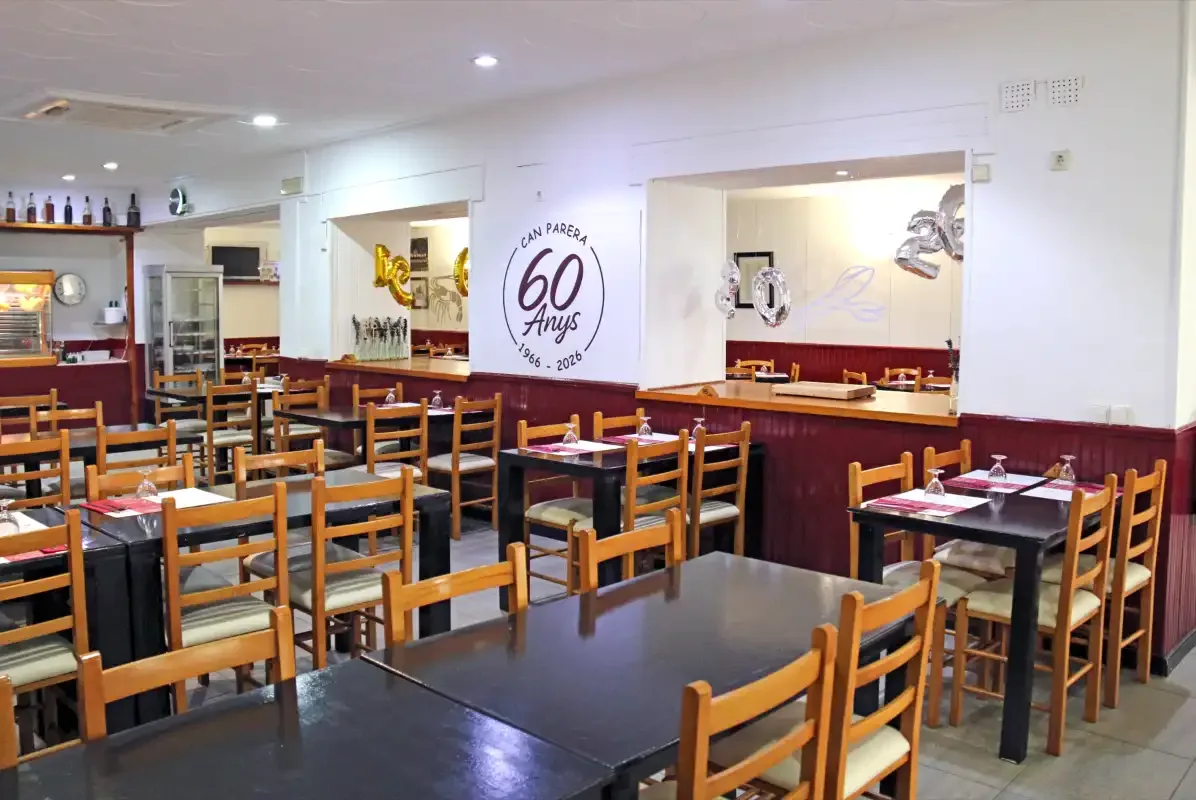 Salón de Can Parera, con mesas de madera y decoración del 60 aniversario, en Parets del Vallès